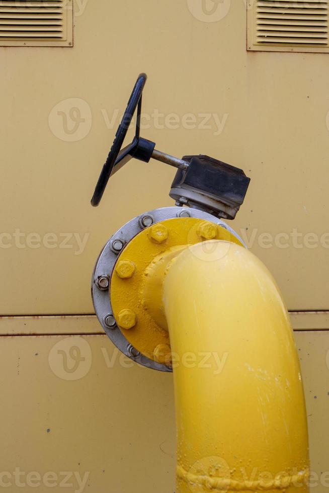 tuyau de gaz jaune avec un robinet. raccords d'oléoducs dans l'industrie pétrolière et gazière. usine de traitement du pétrole et du gaz avec raccords de pipeline. soupape de sécurité industrielle. photo