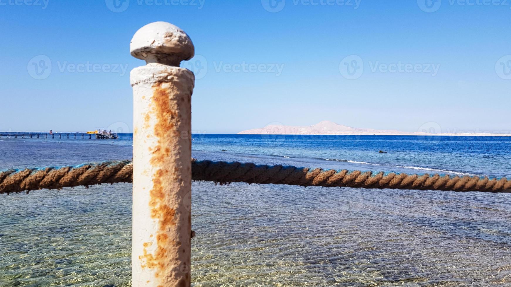 long ponton sur la mer rouge en egypte. ponton pour la descente dans l'eau. pont en bois sur le territoire de l'hôtel amway à sharm el sheikh avec des clôtures métalliques et une corde au-dessus de la mer avec des vagues photo