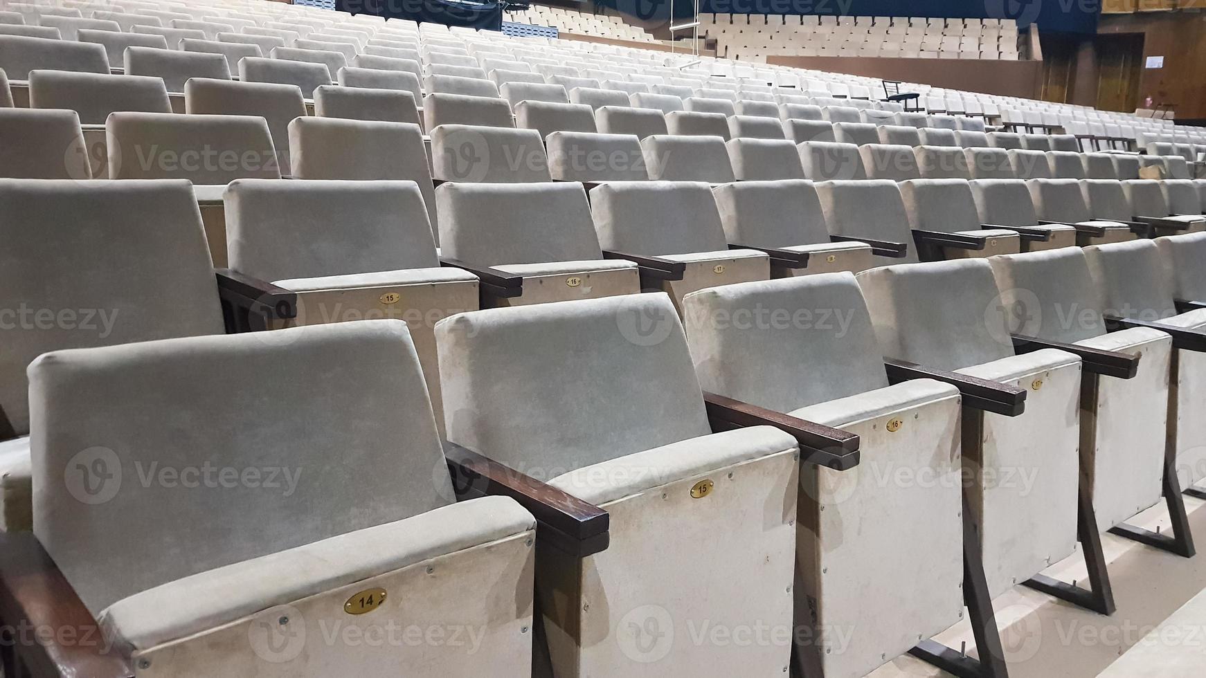 beaucoup de vieilles chaises rembourrées beiges sans personnes dans la salle pour des spectacles et des films. arrière-plan de nombreuses chaises dans les tribunes d'une salle de concert ou d'un théâtre. photo