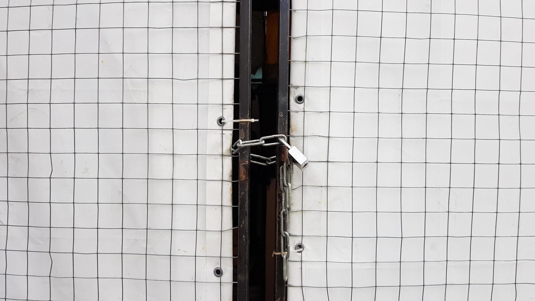 cadenas fermé sur un hangar à partir d'une grille et d'une bannière blanche photo