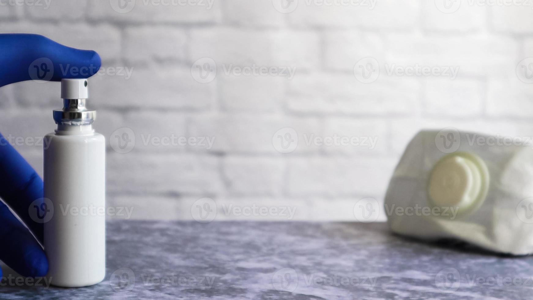 bouteille antiseptique blanche et masque d'un médicament protecteur sur une table grise, sur fond de mur de briques blanches. prévention de la maladie à coronavirus covid-19 lors d'une épidémie de virus de la grippe photo