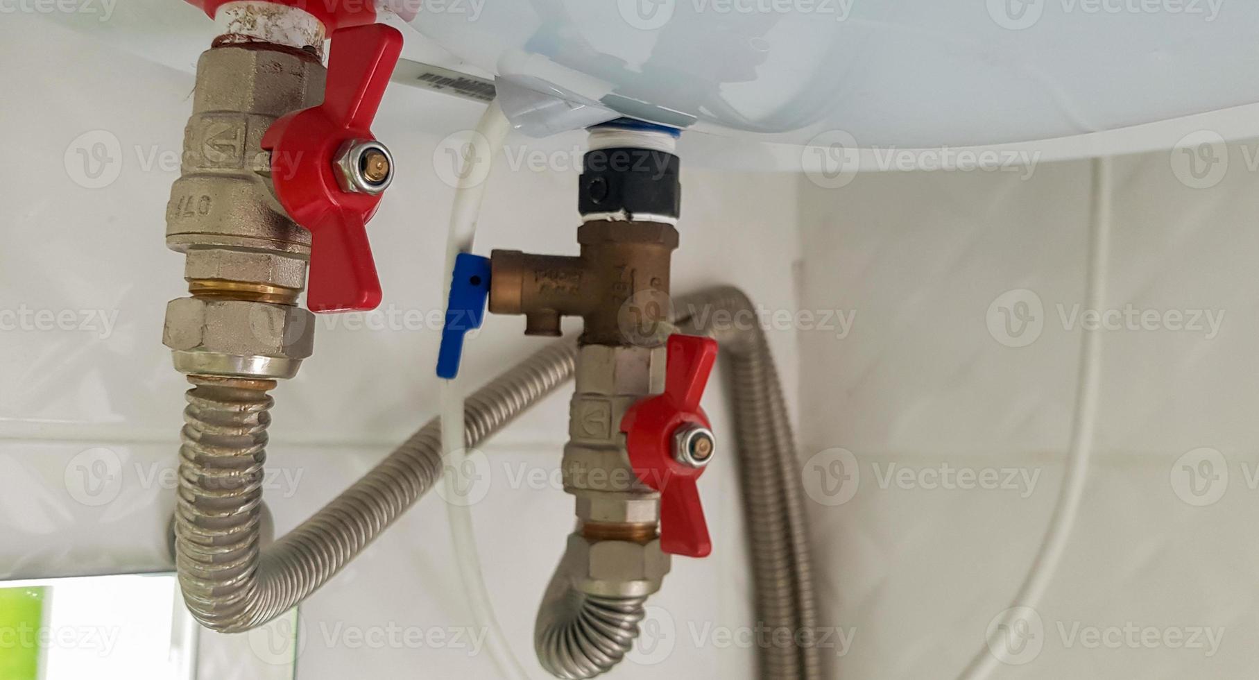 raccordement de l'alimentation en eau, eau chaude et eau froide à la chaudière. tuyau d'eau chaude et froide dans la salle de bain. raccords de plomberie pour un chauffe-eau électrique domestique. photo