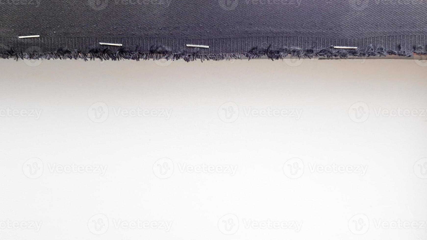fond blanc avec une bande de tissu noir perforée avec des agrafes sur une planche de bois. abstrait avec espace de copie. photo