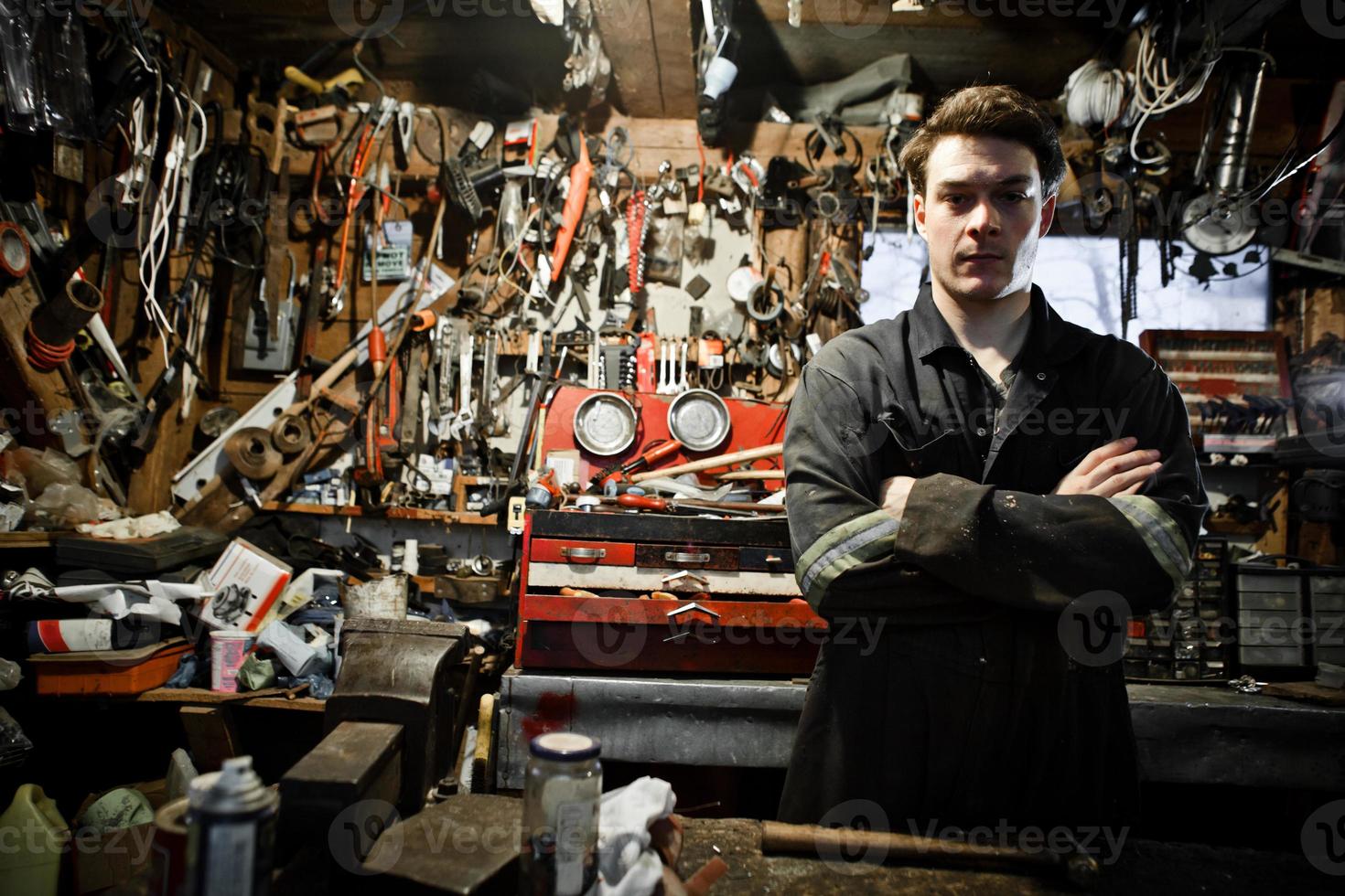 travailleur bras croisés dans un hangar et beaucoup d'outils suspendus photo