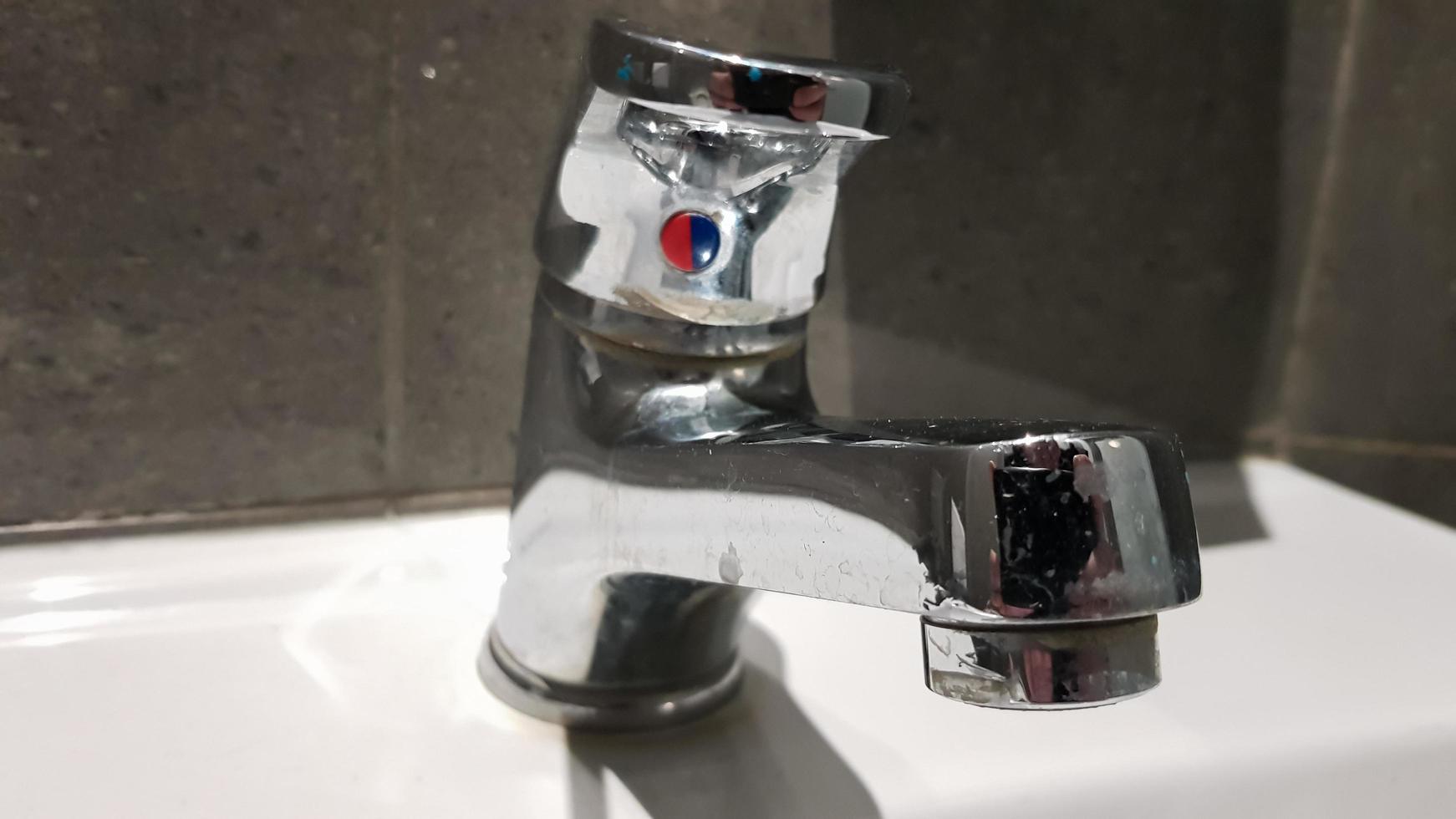 lavabo en céramique blanche avec robinet chromé dans les toilettes avec carrelage gris photo