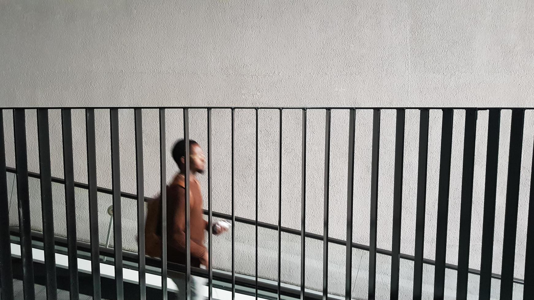 une silhouette d'un homme noir descendant les escaliers derrière la balustrade en métal. photo