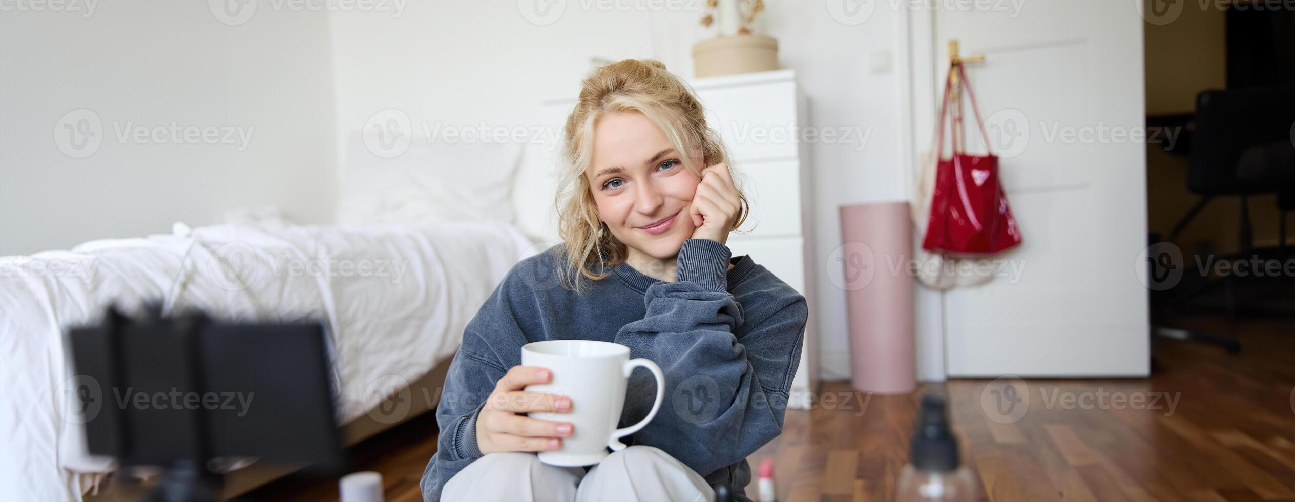 proche en haut portrait de magnifique blond femme, fille est assis dans sa chambre, Est-ce que se maquiller, enregistrements pour social médias, les boissons thé, détient agresser et sourit à caméra photo