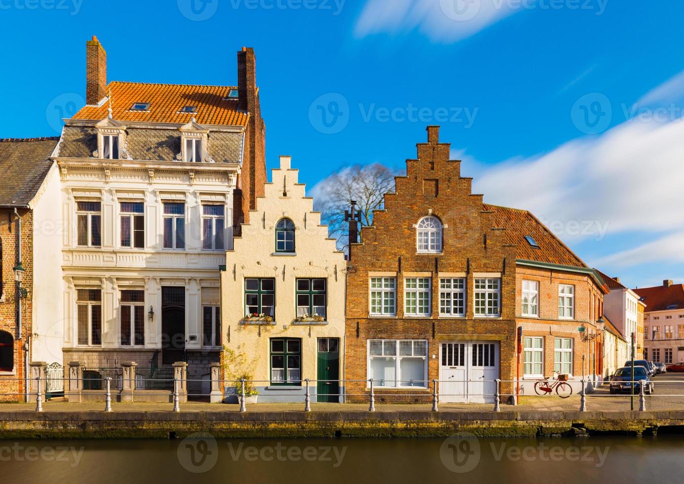 bruges, brugge, belgique - vue sur la rue des vieilles maisons résidentielles de style architectural traditionnel. façades des bâtiments historiques et canal avec eau. photo