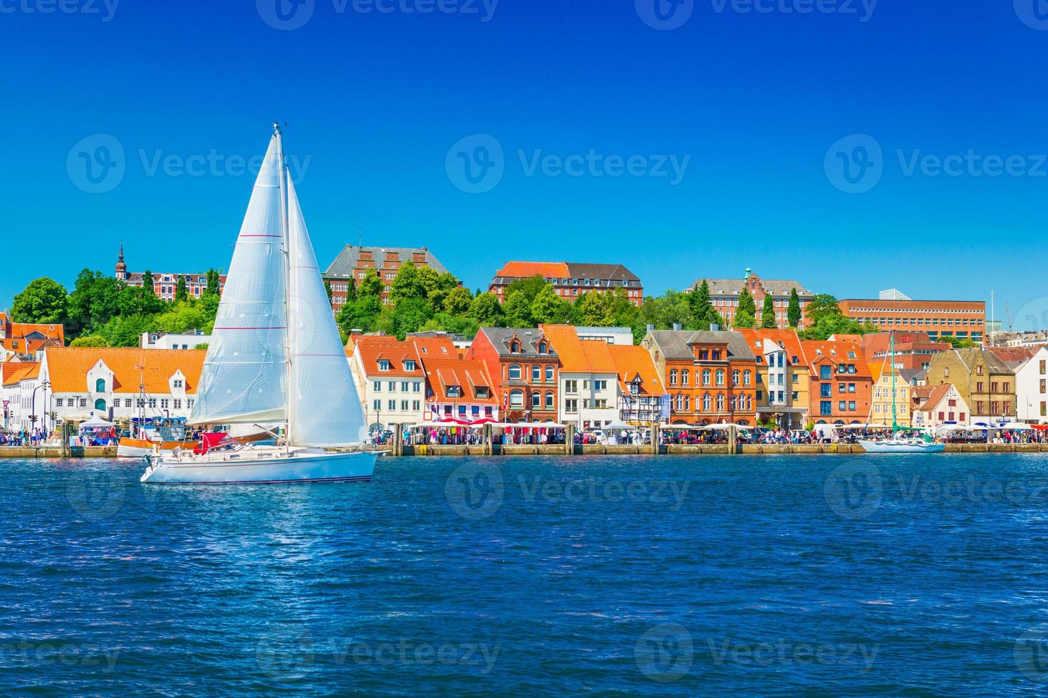 beau panorama d'une ville portuaire européenne. un yacht navigue contre l'horizon de la ville de flensburg, allemagne photo