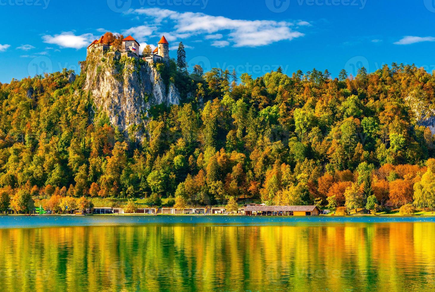 vue pittoresque sur le lac de saignée en automne, slovénie. beau paysage avec des arbres colorés sur les collines se reflétant dans l'eau photo