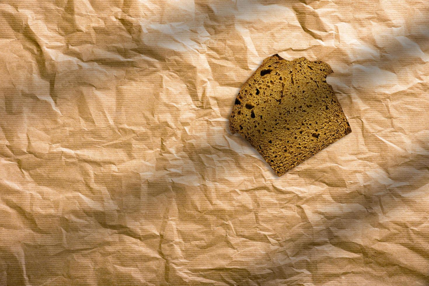 pain de seigle tranché sur un fond marron isolé. tranches de pain brun enveloppées dans du papier brun. photo