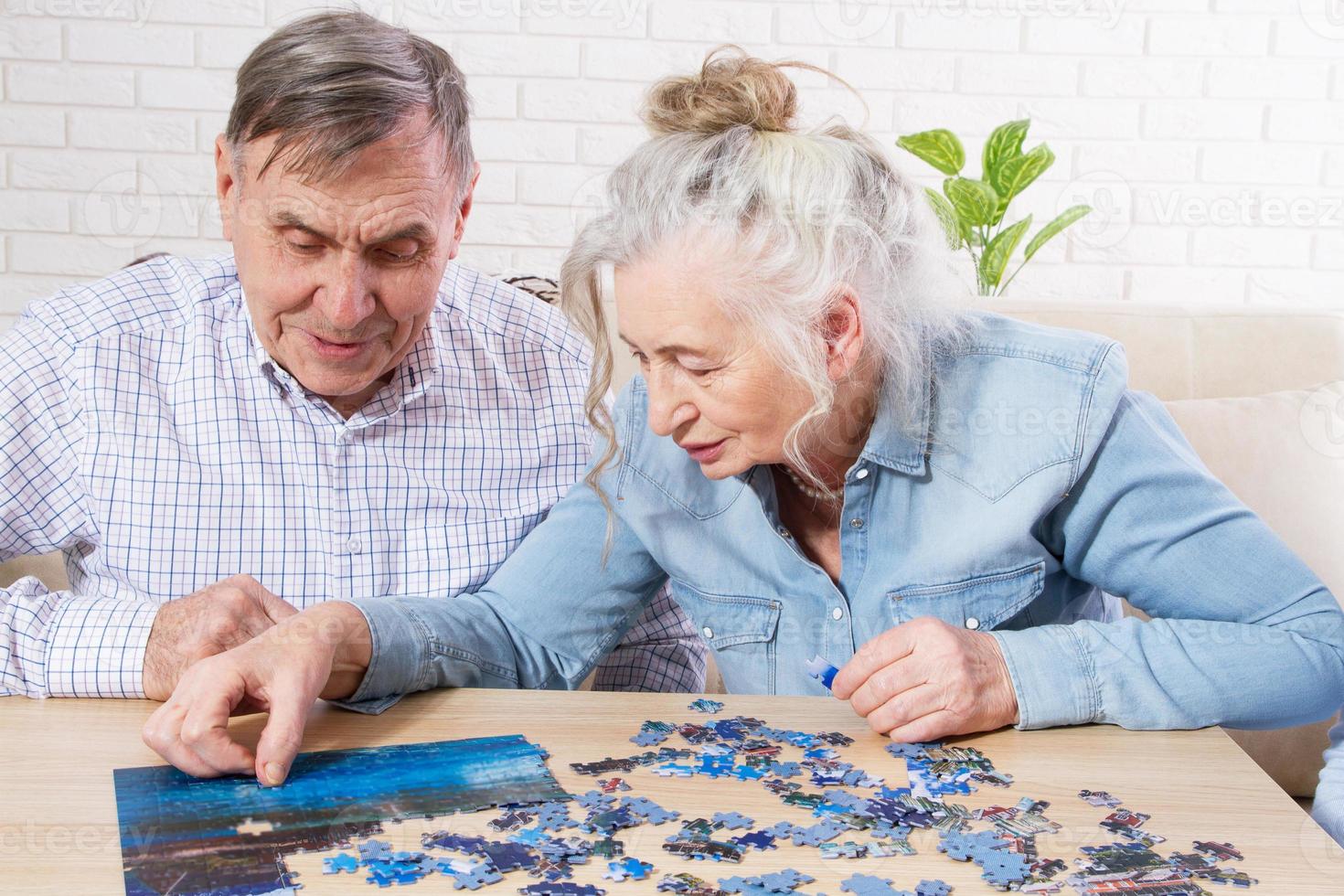 couple de personnes âgées résolvant un puzzle ensemble à la maison photo