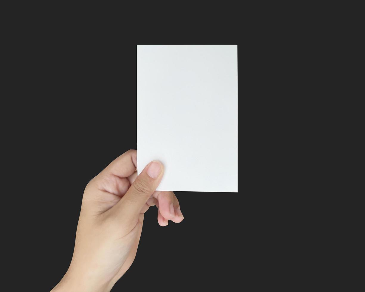 un gros plan de deux mains tenant un papier blanc vierge. montrant un modèle de carte de visite virtuelle sur fond noir. photo