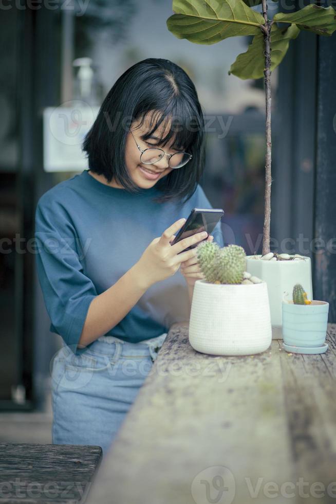 adolescent asiatique utilisant un téléphone portable prenant une photo de cactus en pot