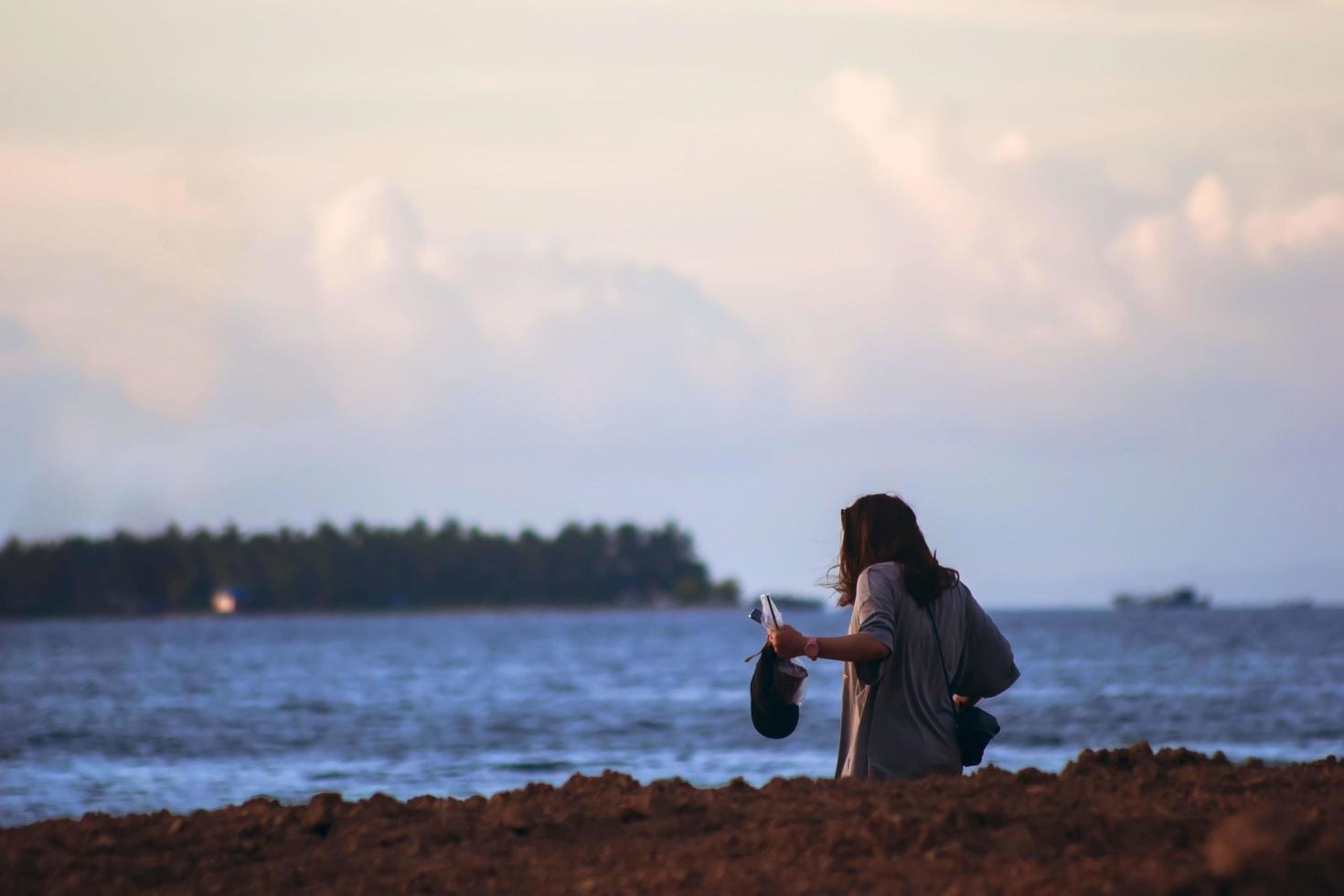 sorong, papouasie occidentale, indonésie, 19 novembre 2021. une fille seule sur la plage prenant un autoportrait avec un smartphone. moi temps. photo