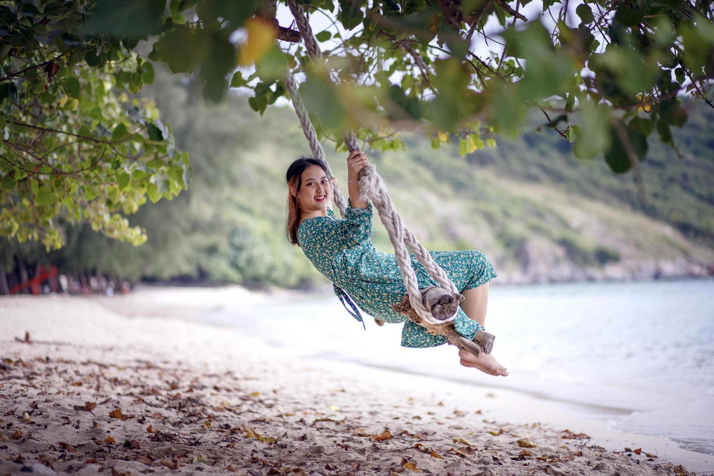 jeune femme asiatique se détendre sur la balançoire à la plage photo