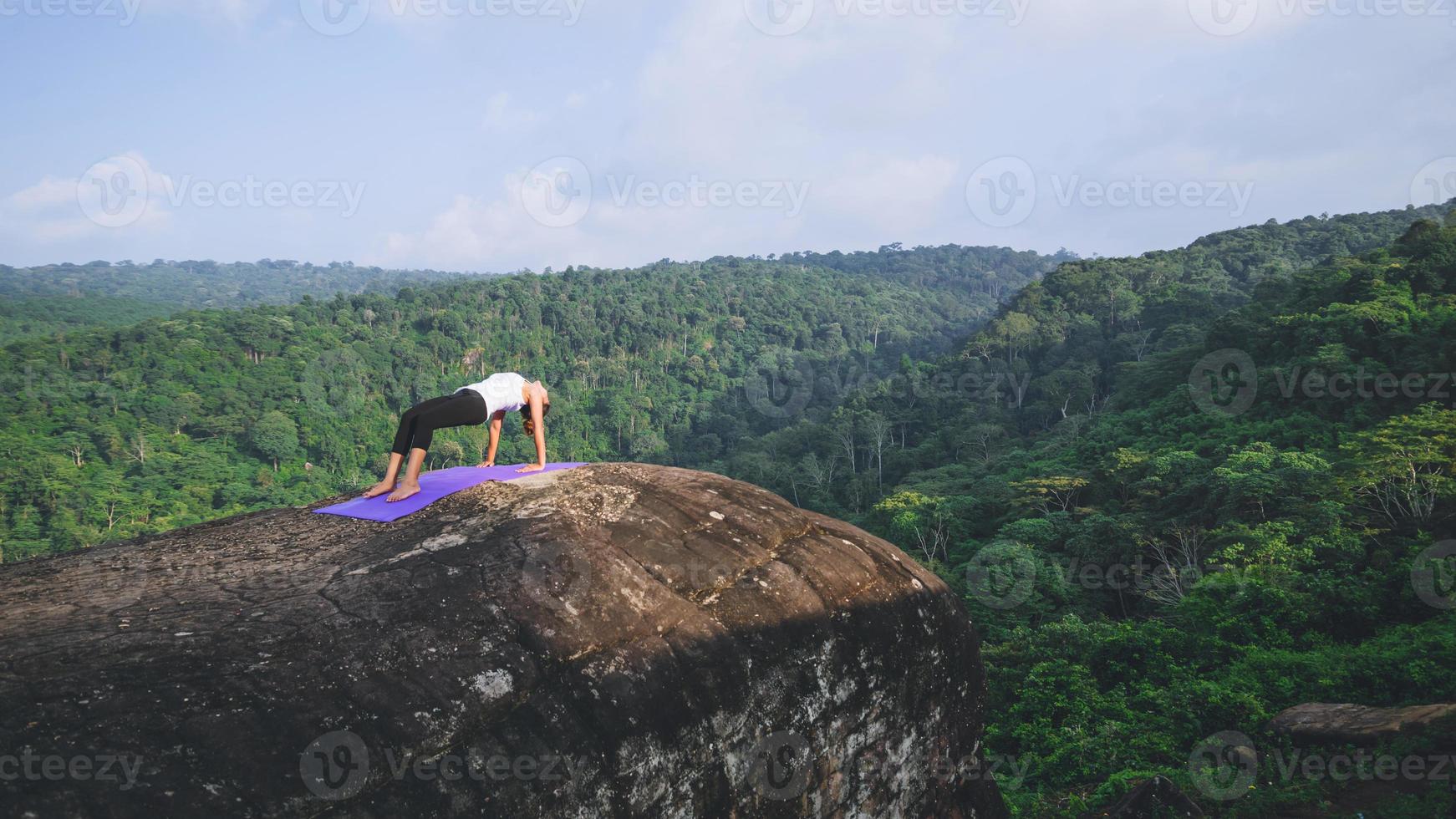 les femmes asiatiques se détendent pendant les vacances. jouer si yoga. sur la falaise rocheuse de la montagne. nature des forêts de montagne en thaïlande. jeune femme pratiquant le yoga dans la nature bonheur féminin. faire du yoga photo