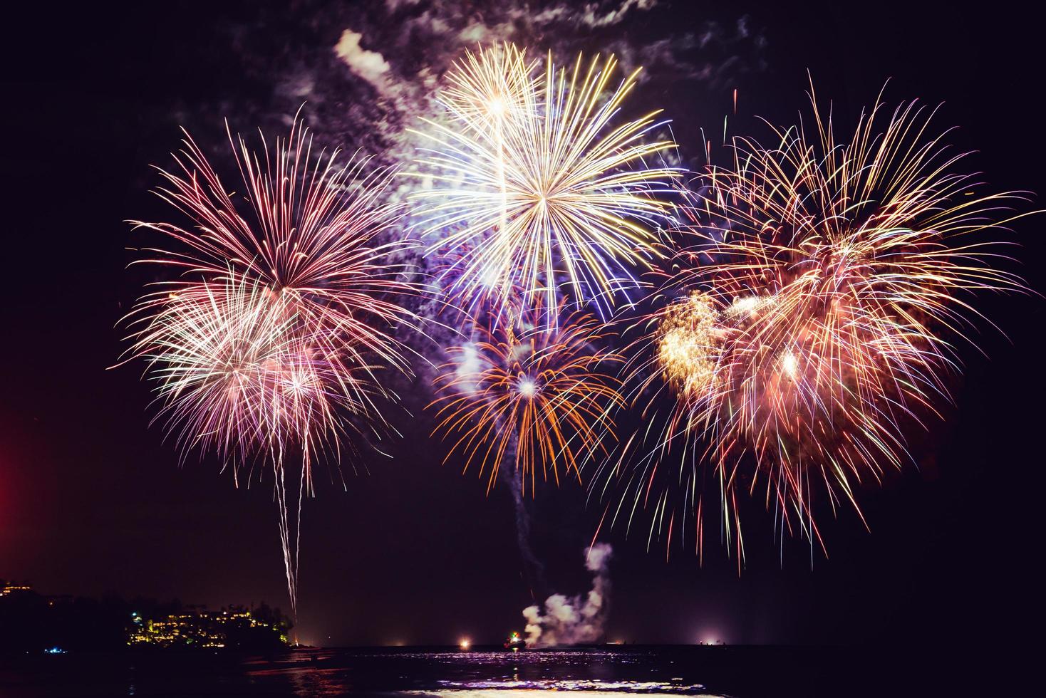 feux d'artifice avec des silhouettes de personnes dans un événement de vacances. feux d'artifice du nouvel an sur la plage. les voyageurs et les gens célèbrent le jour de l'an à kamala beach phuket, thaïlande. photo