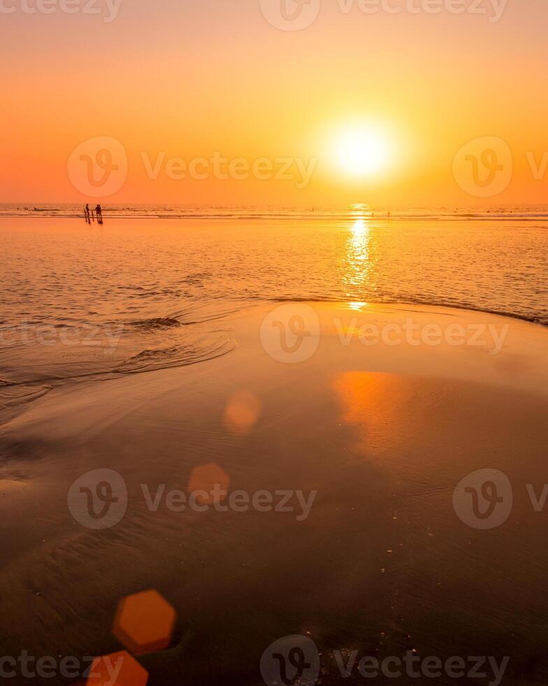 une coloré le coucher du soleil ou lever du soleil sur le bord de mer avec une sablonneux plage avec impuretés de volcanique cendre. Mandrem, allez, Inde. photo