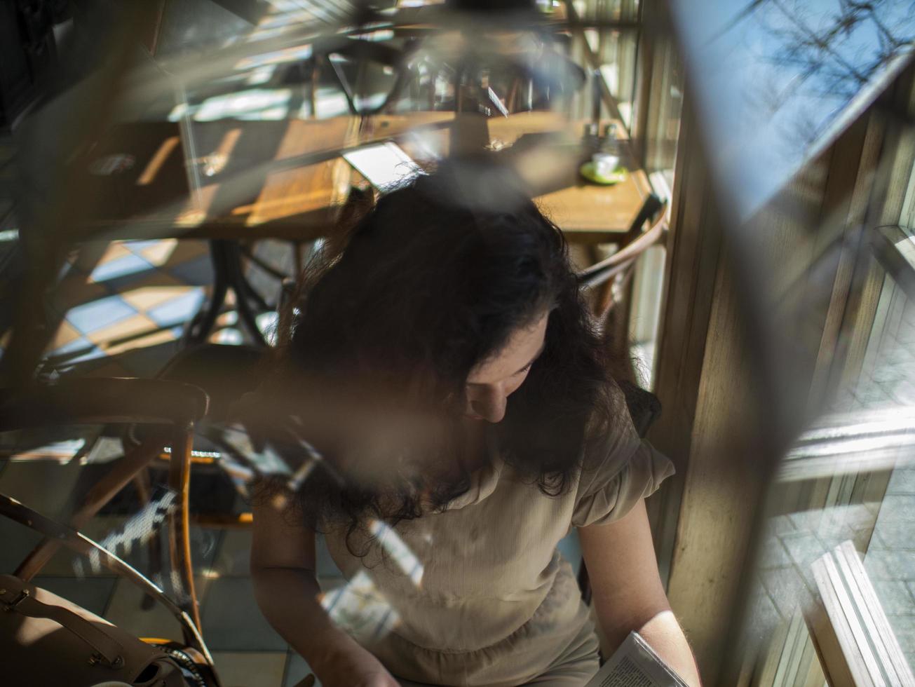 fille aux cheveux bouclés est assise à une table dans un café photo