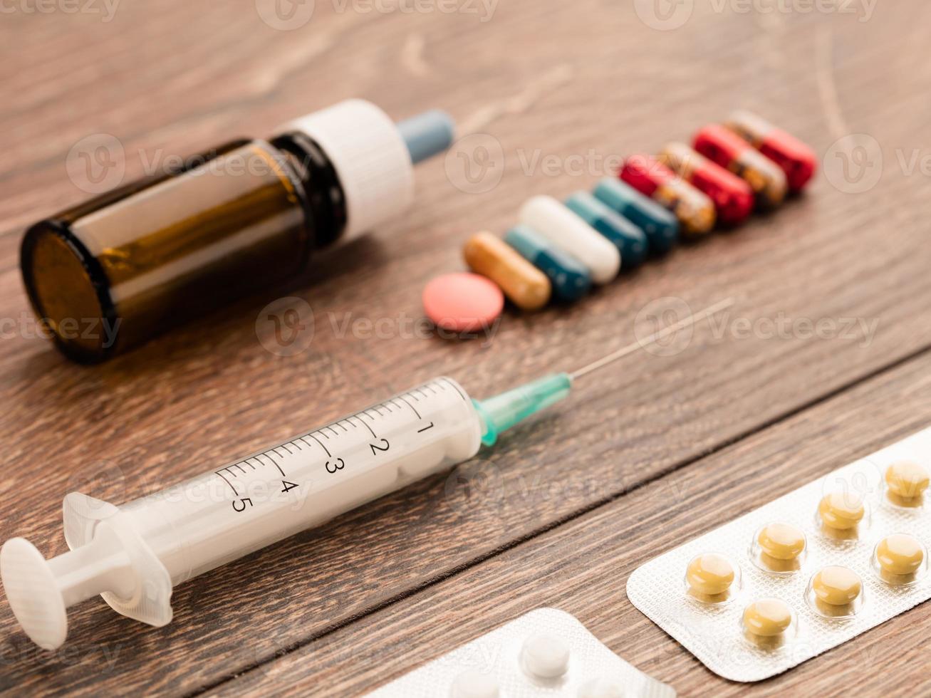 seringue et capsule, ampoule médicale et comprimés sur une table en bois. photo