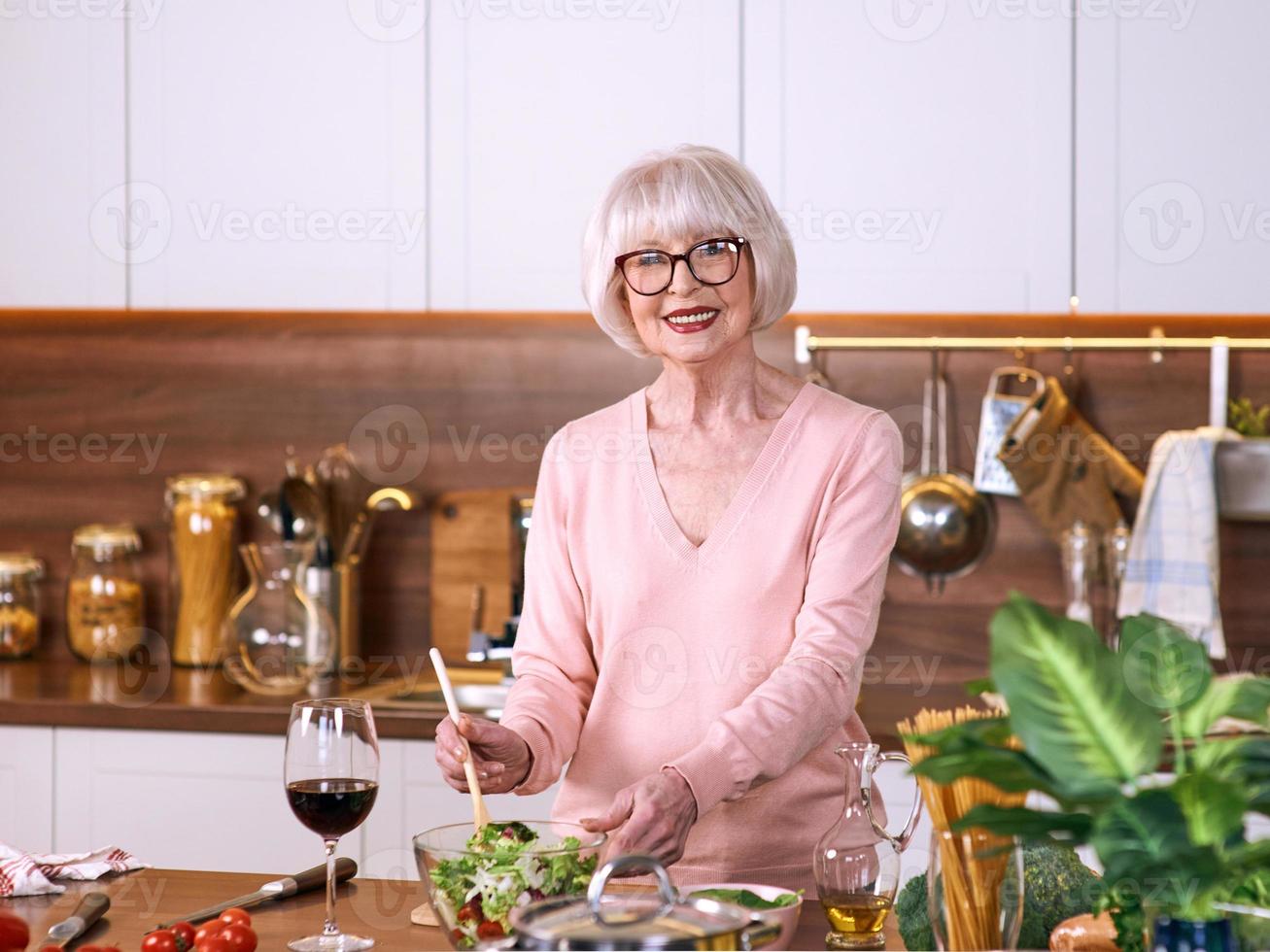 femme joyeuse senior cuisine dans une cuisine moderne. nourriture, compétences, concept de mode de vie photo