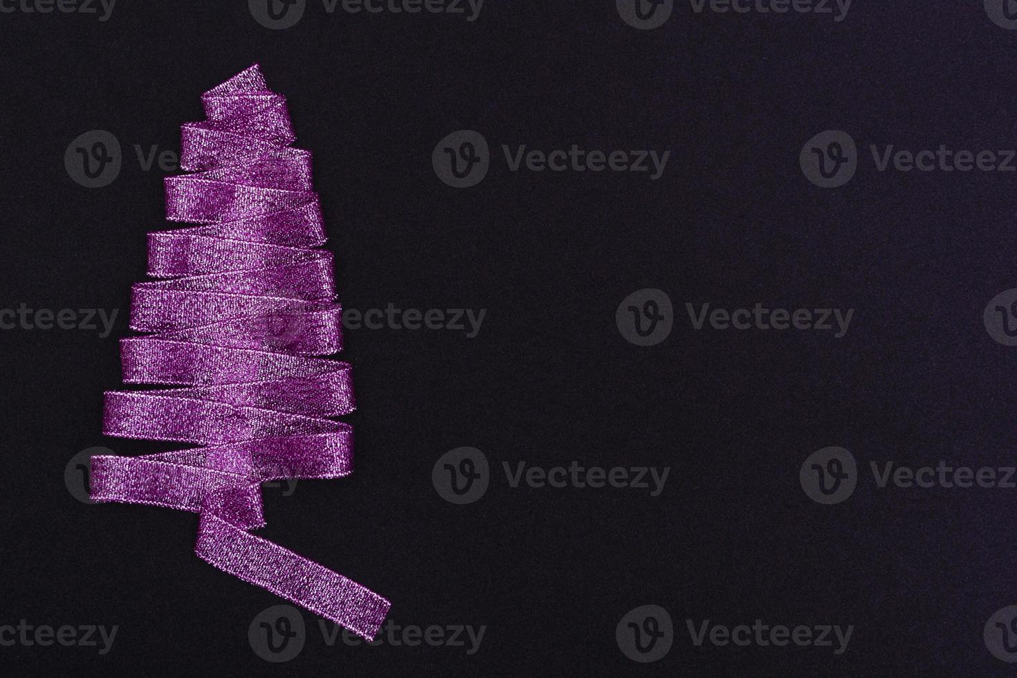 notion de noël. arbre de noël violet fait de rubans sur fond noir. avec modèle d'espace de copie pour cartes postales, emballage. photo