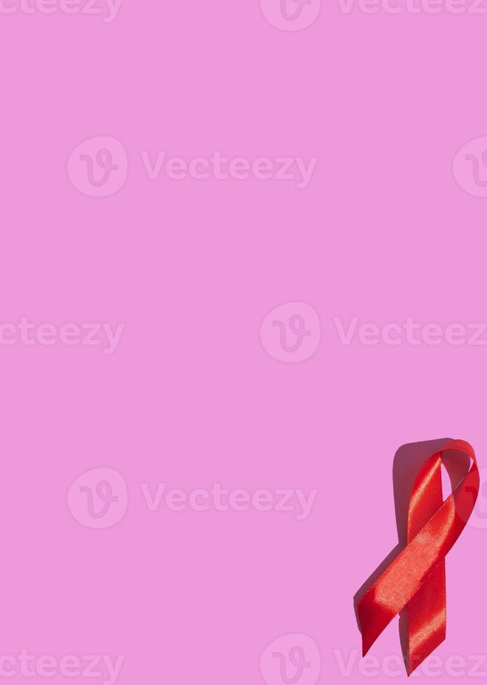 journée internationale du sida. ruban rouge avec une ombre dure sur fond rose. aide au concept de sensibilisation. verticale photo