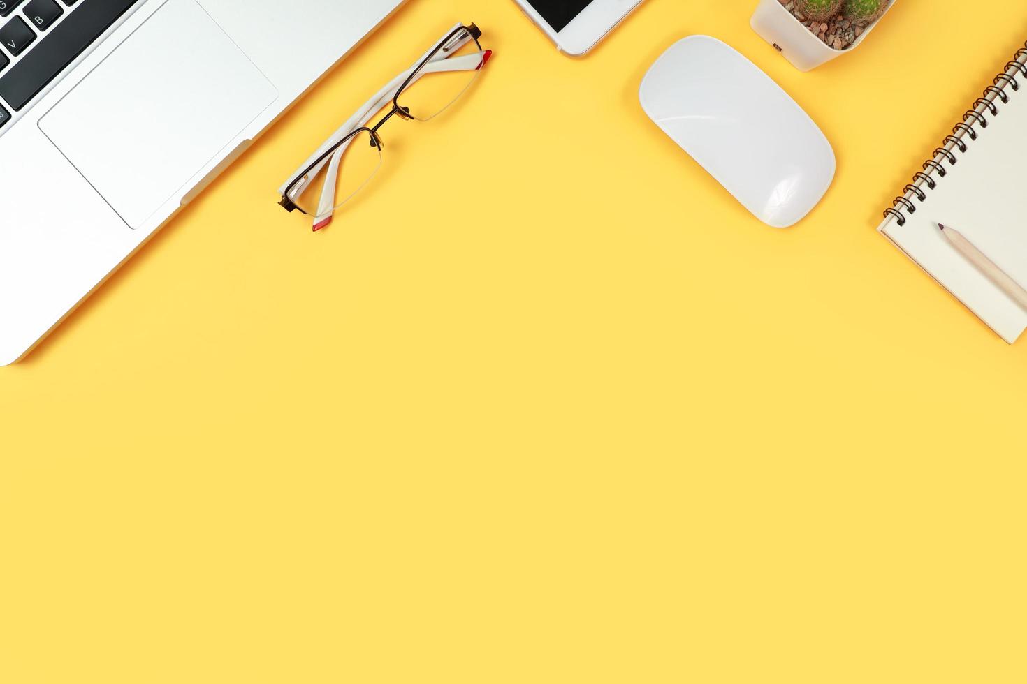 table d'espace de travail avec ordinateur portable, fournitures de bureau, tasse à café, téléphone portable et tasse à café sur fond jaune photo
