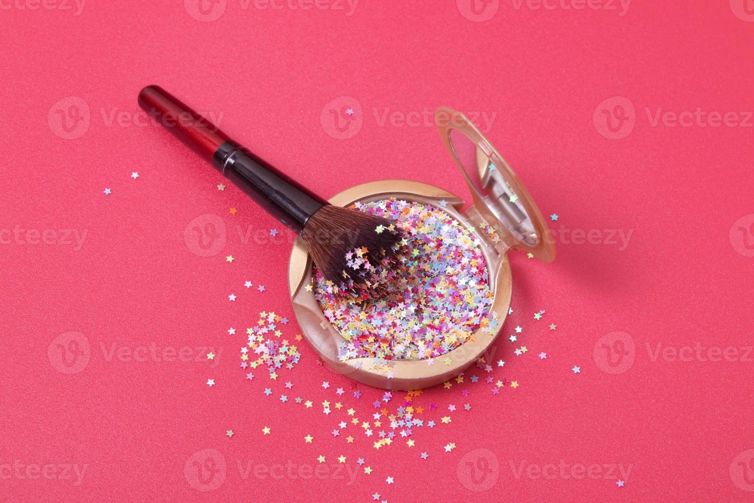 poudre de maquillage et pinceau cosmétique avec étoiles scintillantes sur fond rouge photo