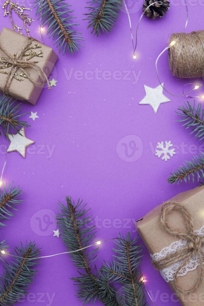 vue de dessus de composition de noël. concept photo vacances de noël et du nouvel an. branches de sapin, jouet d'arbre de Noël, cadeaux, ficelle, cônes, étoiles, guirlandes et flocons de neige sur fond violet. mise à plat