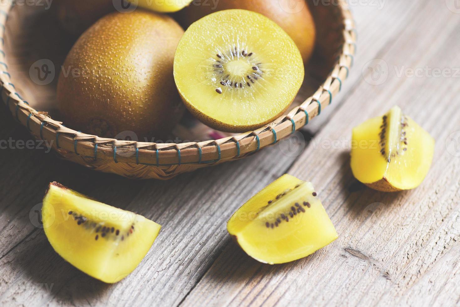 tranche de kiwi sur panier, gros plan de kiwi jaune sur fond de bois. photo