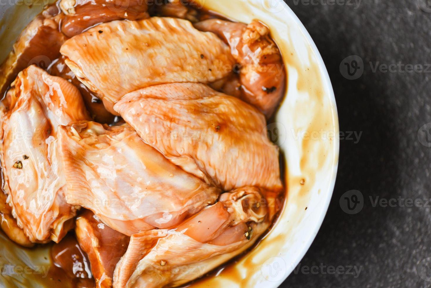 ailes de poulet crues avec sauce aux herbes et épices marinées pour griller ou cuire au four. photo