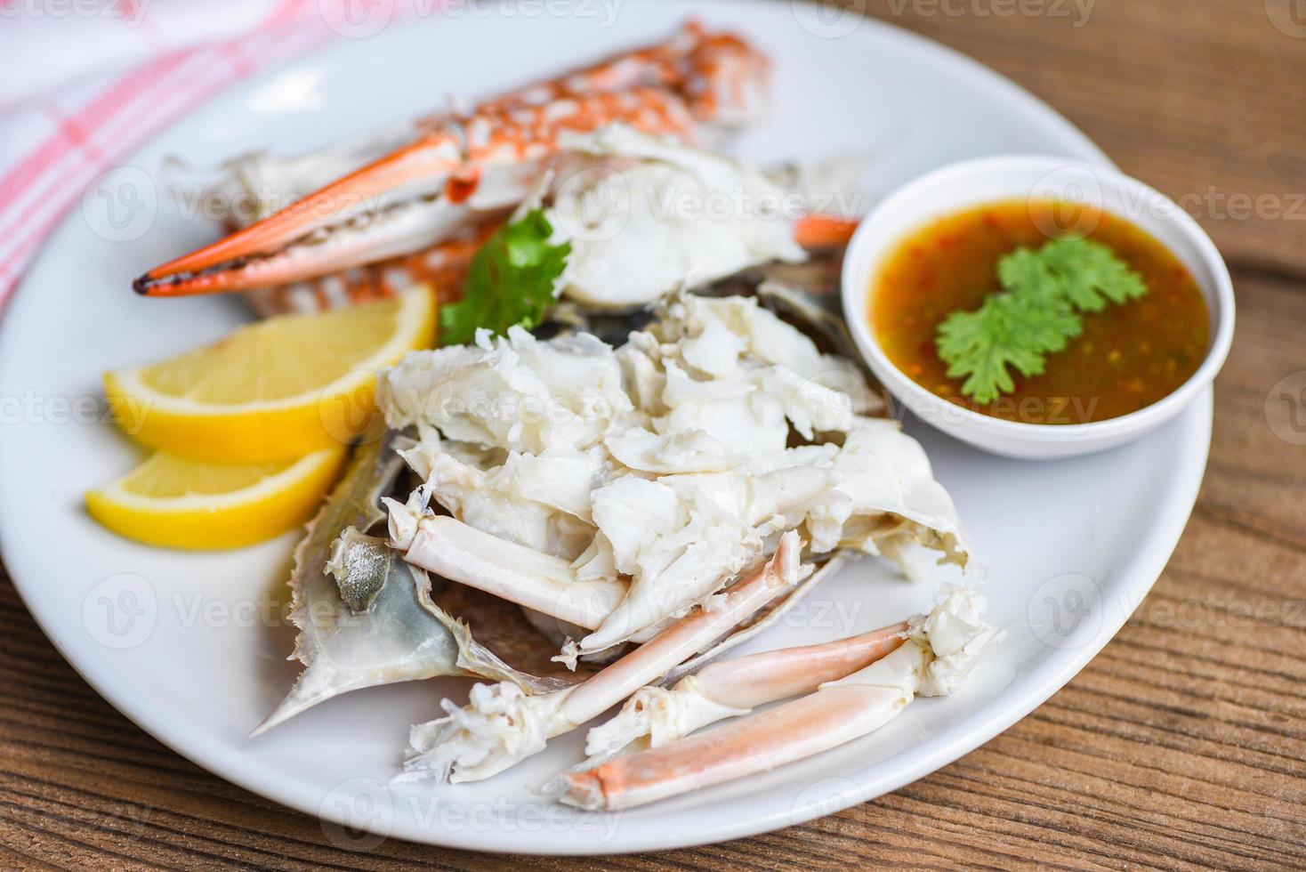 chair de crabe - pinces et pattes de crabe cuites sur assiette blanche et sauce aux fruits de mer sur la table , crabe bleu nageur photo