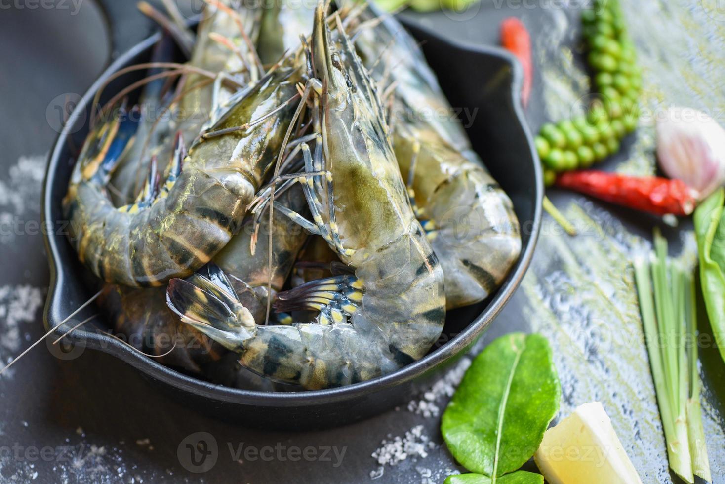 crevettes crues crevettes sur bol avec herbes et épices pour soupe aigre-douce épicée cuite, crevettes tigrées fraîches. photo