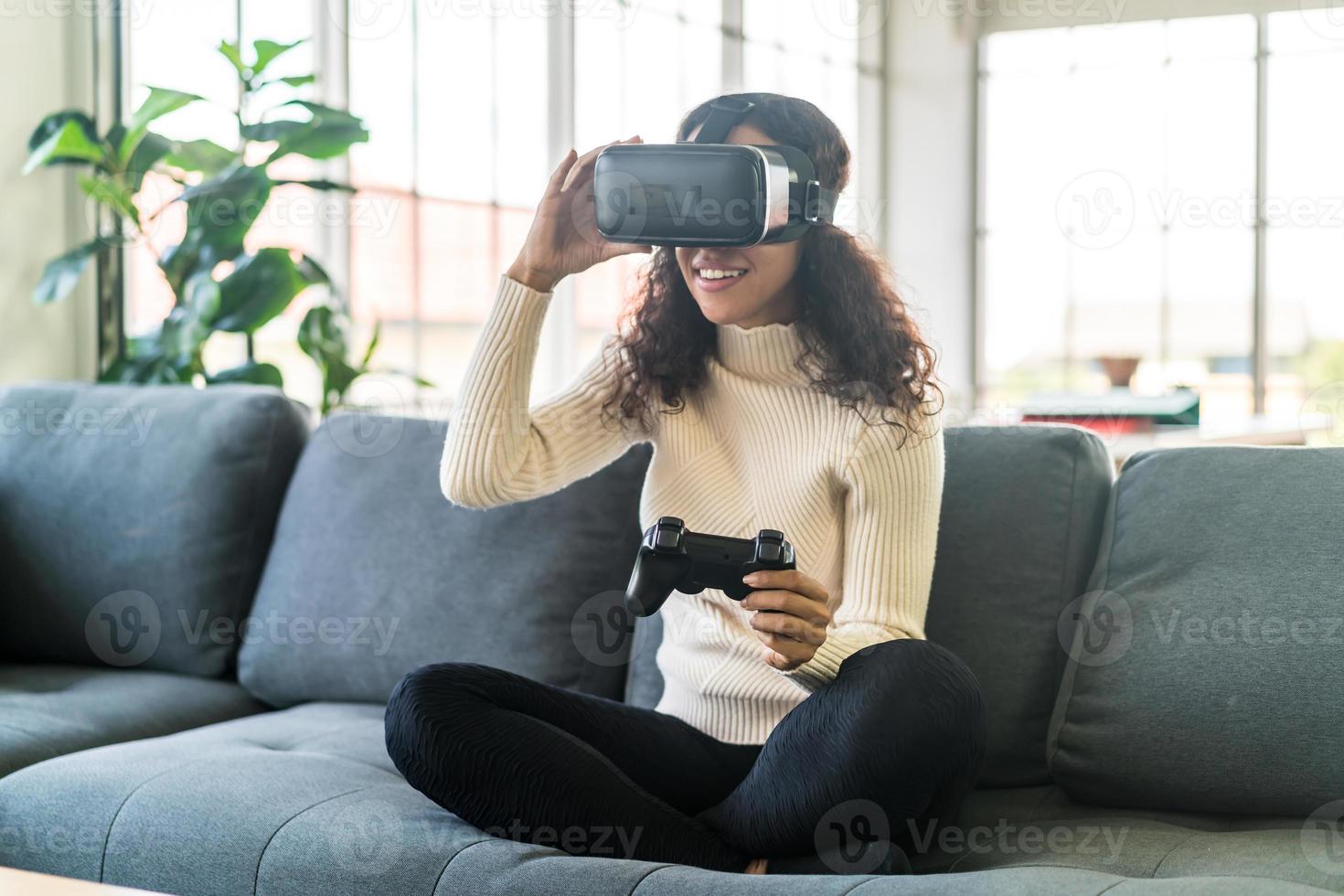 femme latine à l'aide d'un casque de réalité virtuelle sur canapé photo