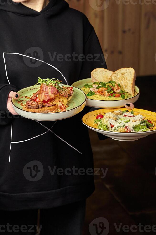 serveuse équilibrage assiettes de Bruschetta, crevette Hoummous, et César salade photo