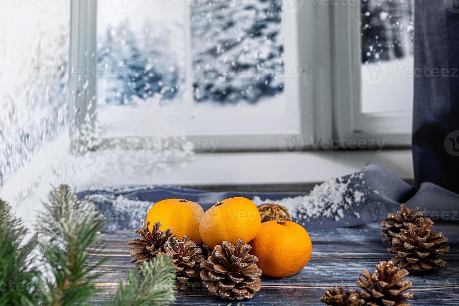 mandarines sur fond gris avec des branches d'un arbre de noël, en arrière-plan une fenêtre avec de la neige. concept de nouvel an. photo