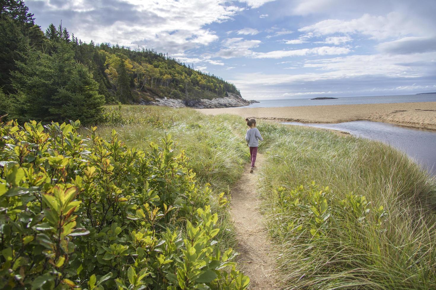 petite fille marchant sur un chemin sablonneux près de l'océan photo