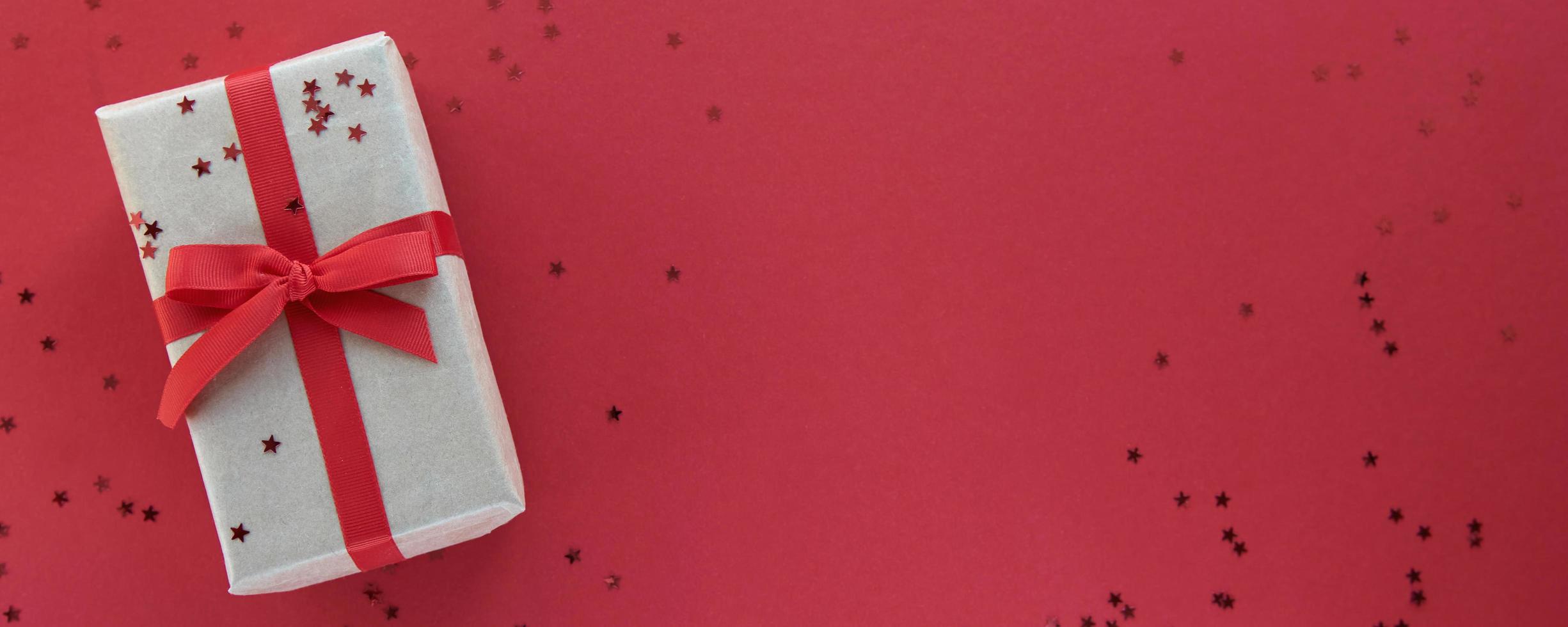 composition de noël. coffret avec décorations en ruban rouge et confettis sur fond coloré de papier pastel. noël, hiver, concept de célébration du nouvel an. mise à plat, vue de dessus, espace de copie photo
