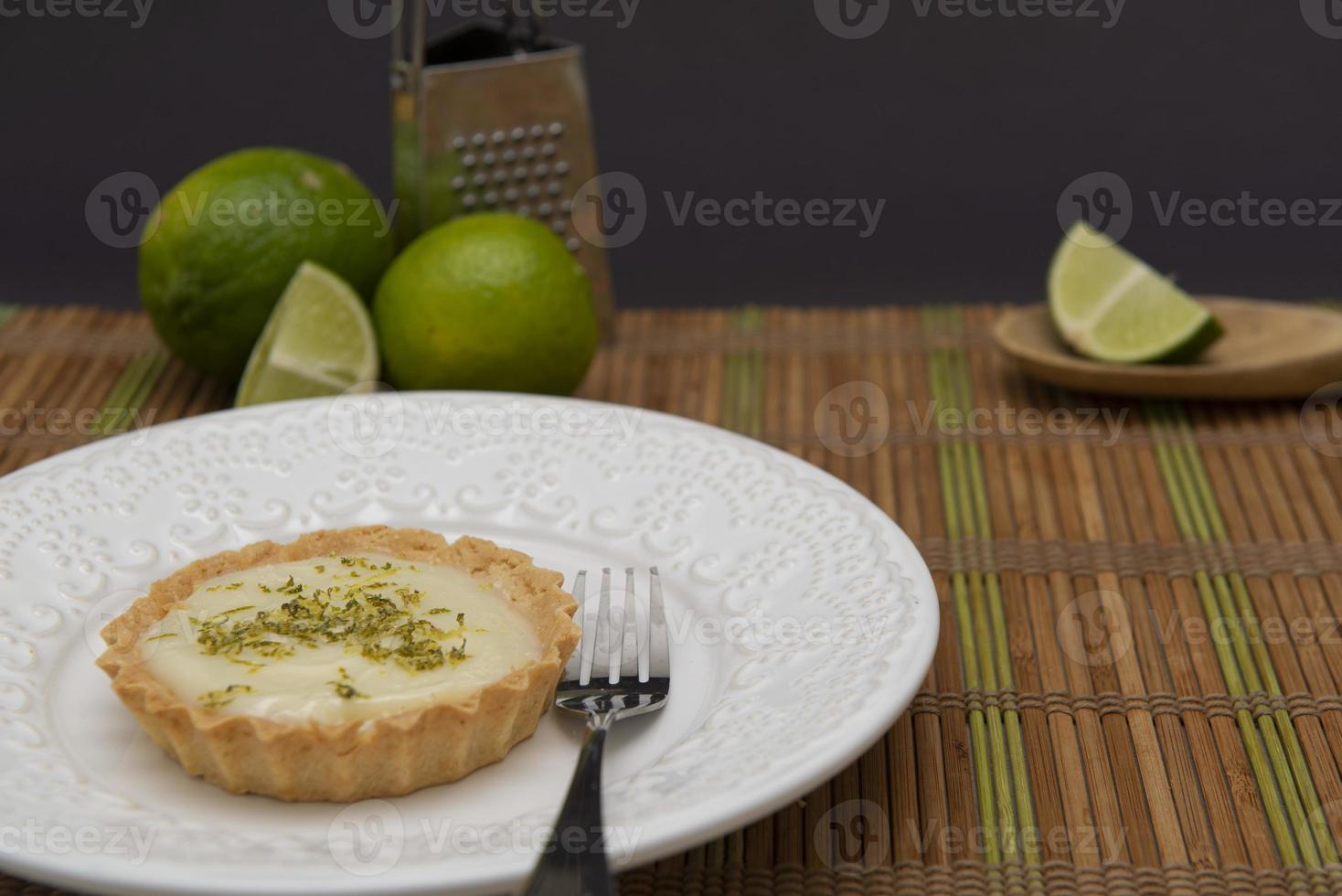 vue latérale d'une tarte au citron sur une assiette avec des tranches de citron sur la table. photo