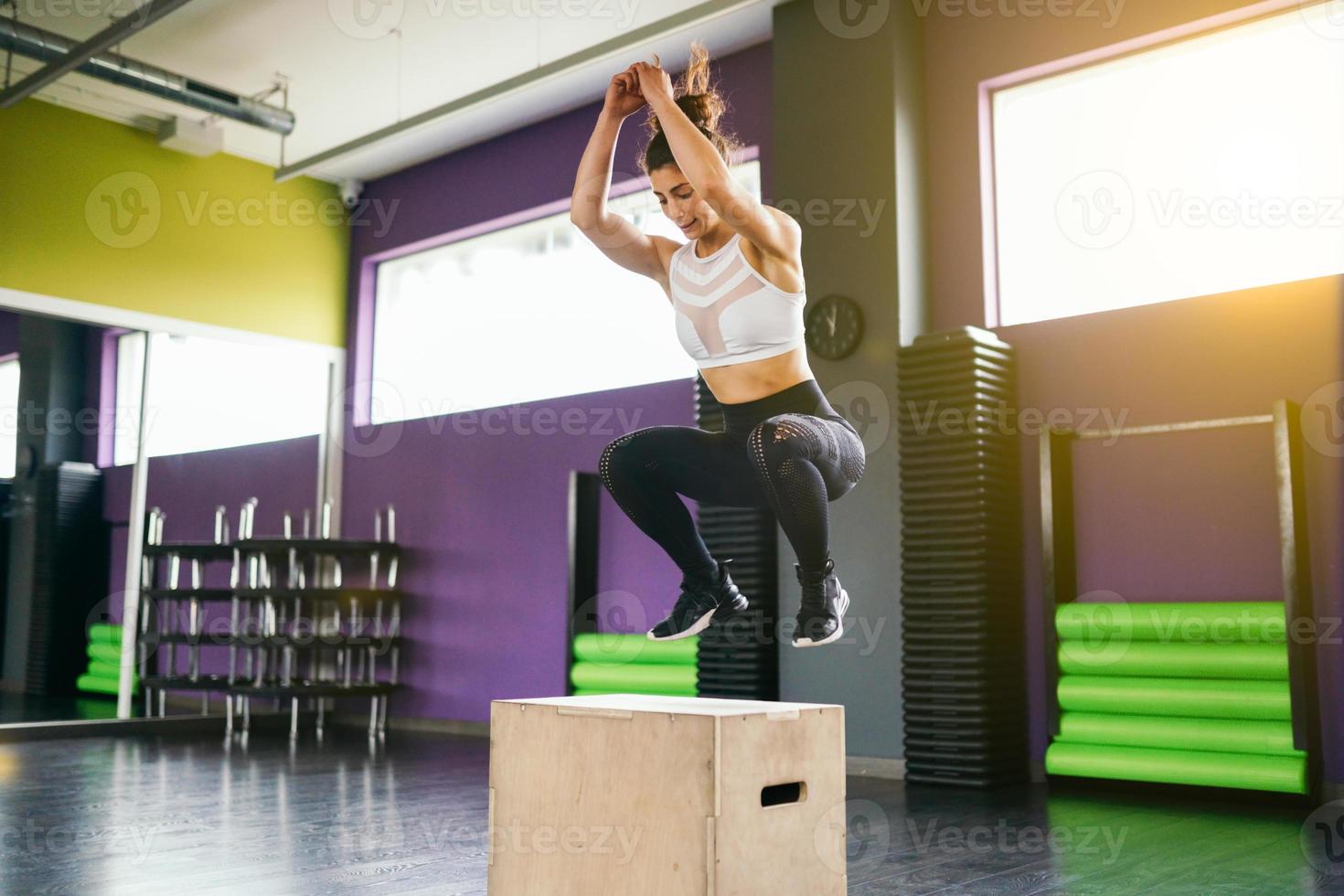 femme de remise en forme sautant sur une boîte dans le cadre d'une routine d'exercice. photo