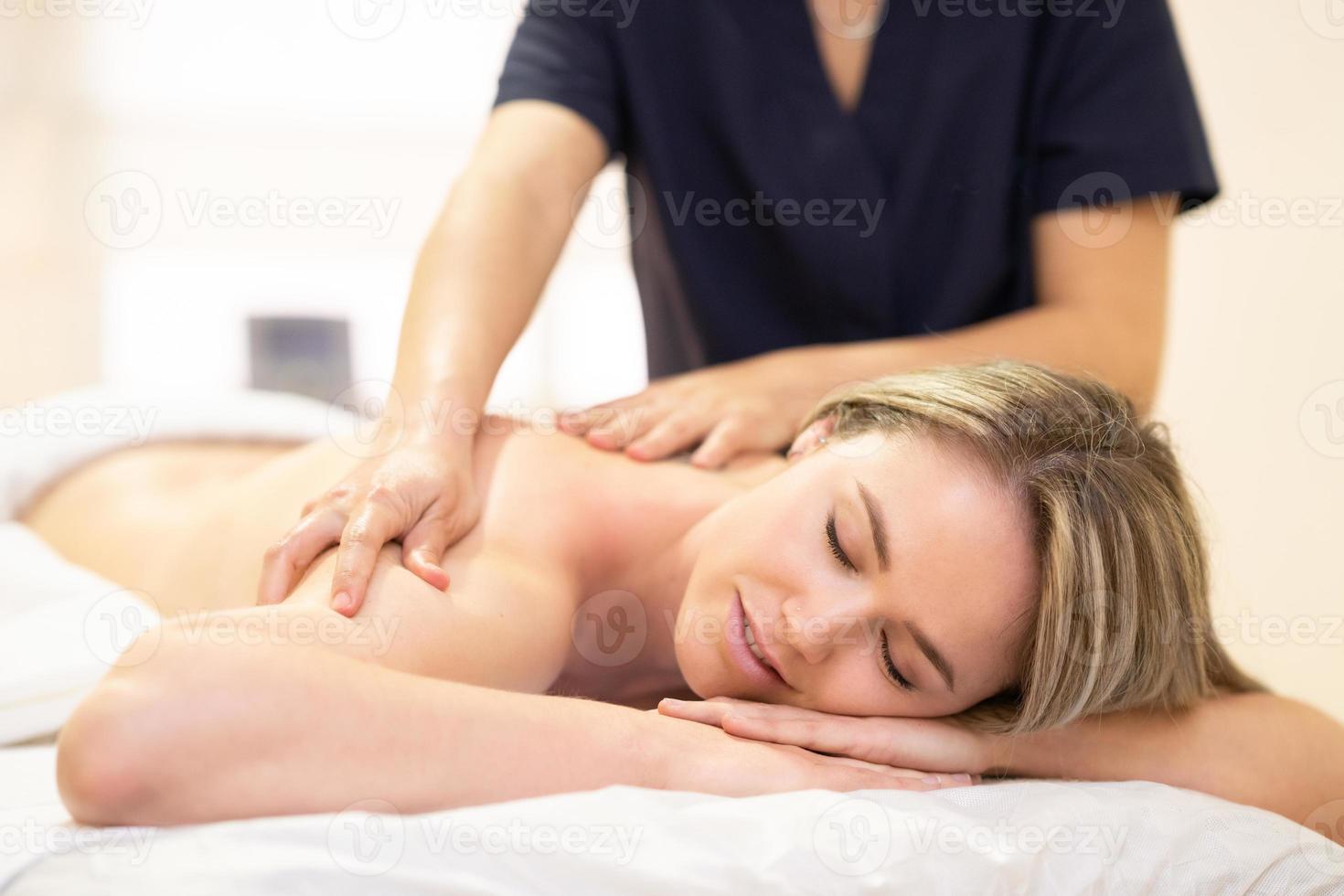 femme allongée sur une civière recevant un massage du dos. photo