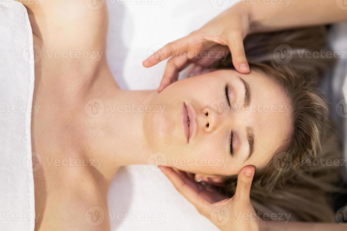 jeune femme blonde recevant un massage de la tête dans un centre de spa. photo