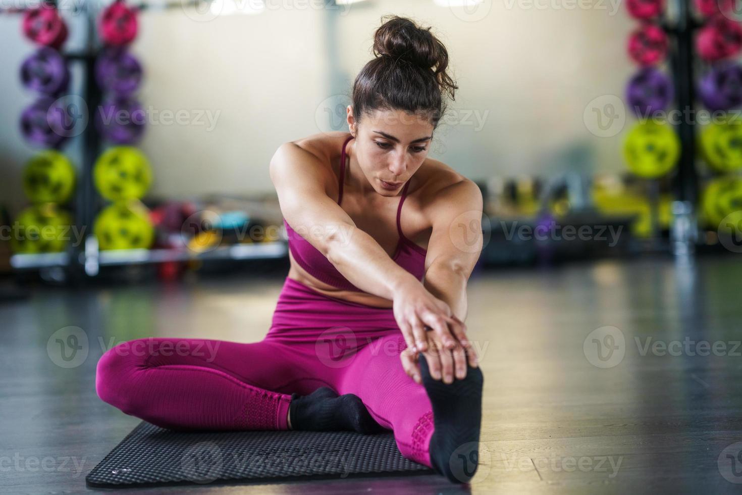 Jeune femme faisant des exercices d'étirement sur un tapis de yoga photo