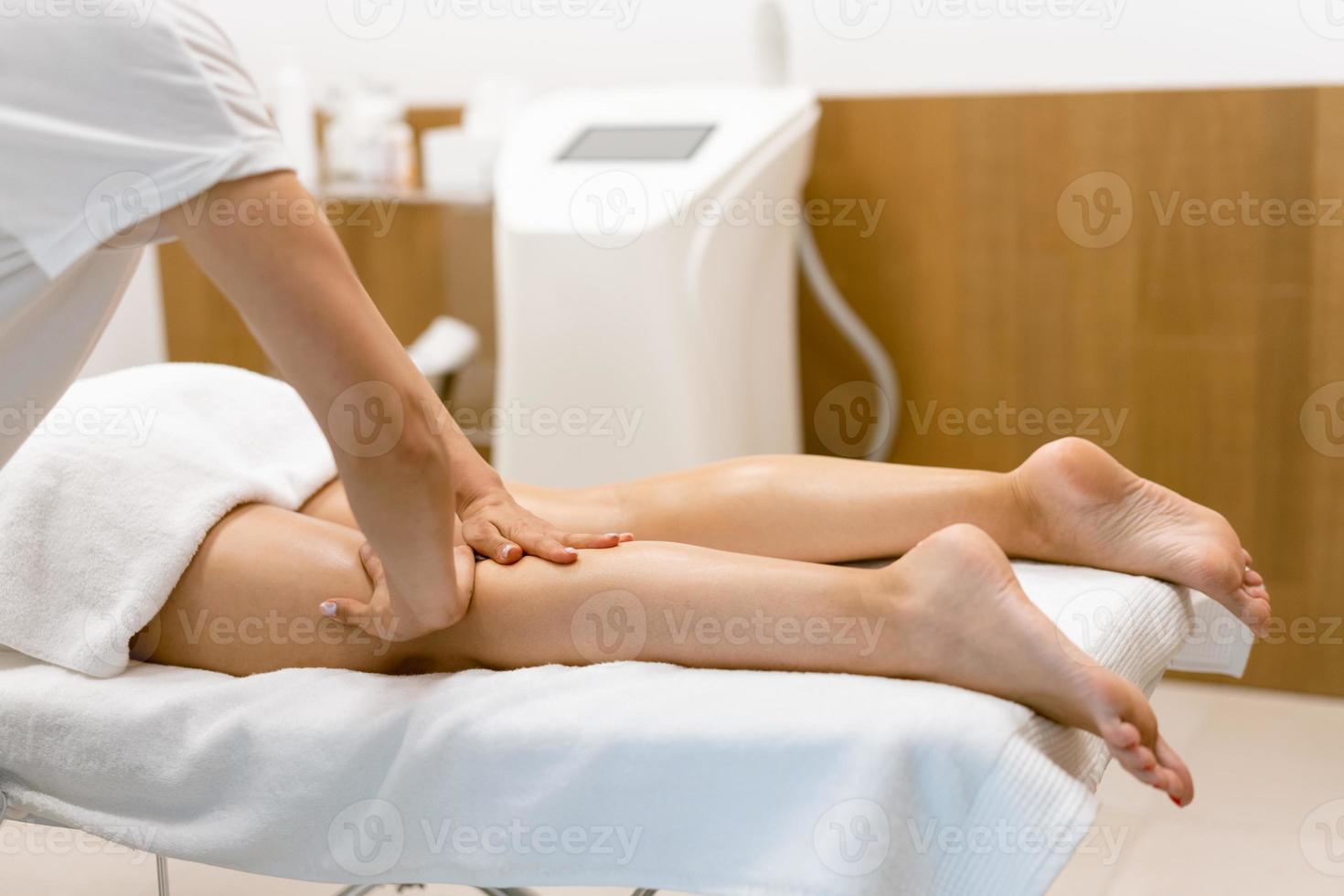 femme d'âge moyen ayant un massage des jambes dans un salon de beauté. photo