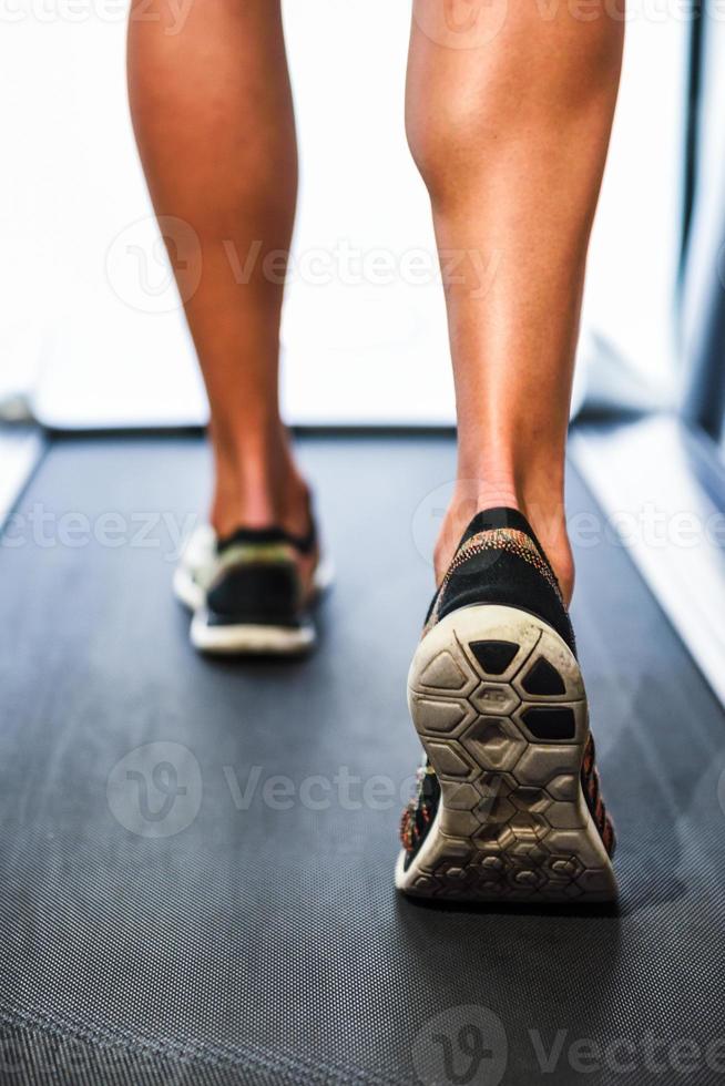 jambes musclées masculines courant sur le tapis roulant au gymnase. photo