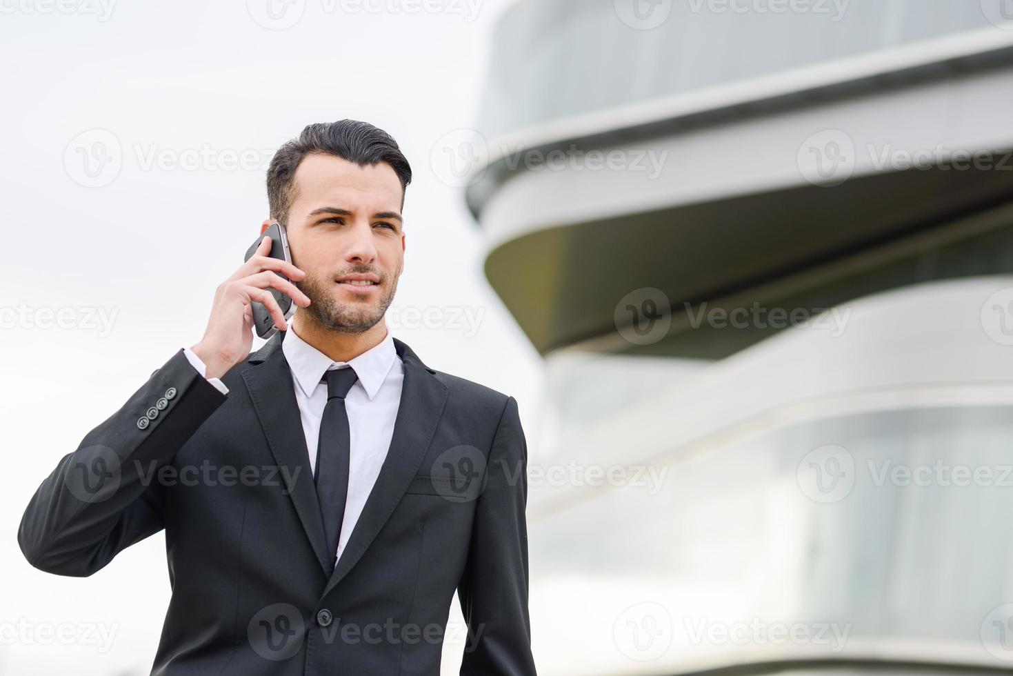 séduisant jeune homme d'affaires au téléphone dans un immeuble de bureaux photo