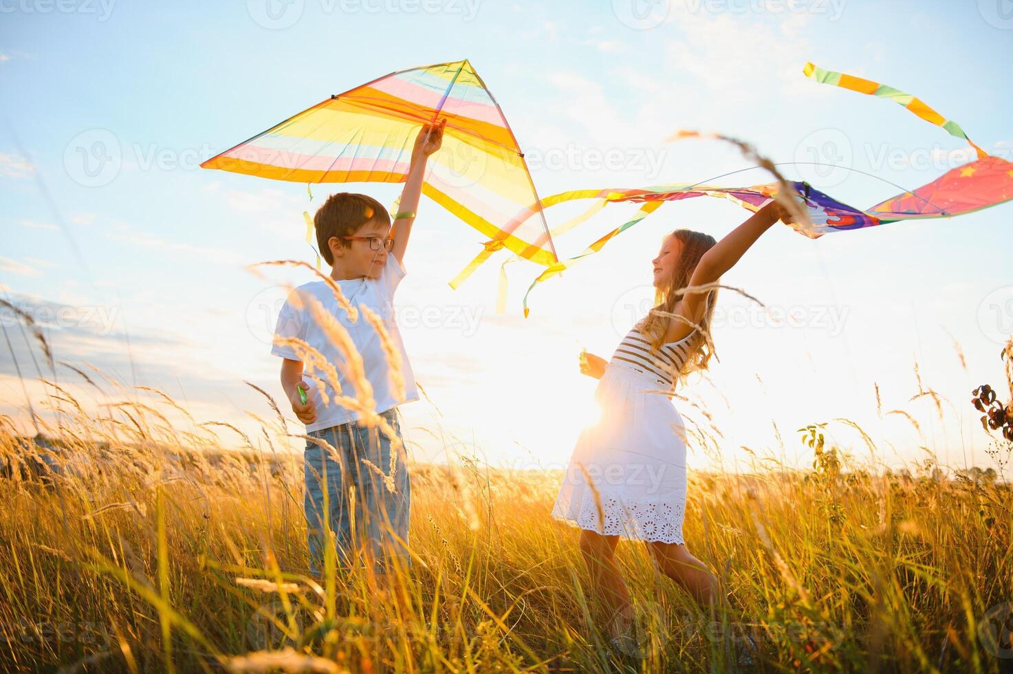 content les enfants lancement une cerf-volant dans le champ à le coucher du soleil. peu garçon et fille sur été vacances. photo