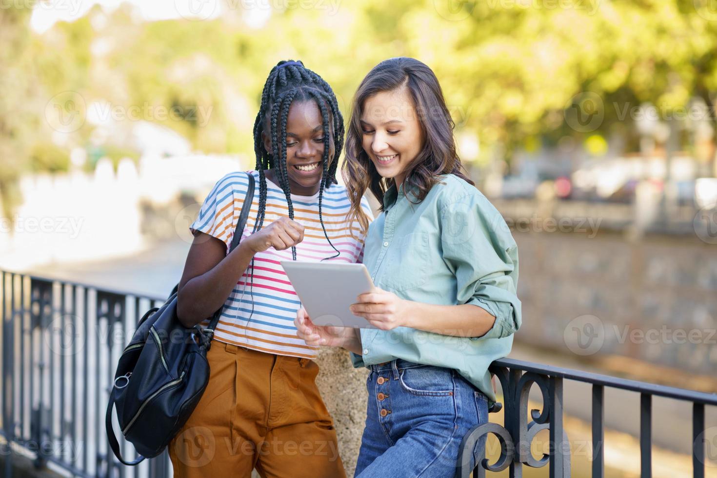 deux femmes multiethniques consultant quelque chose sur une tablette numérique. photo